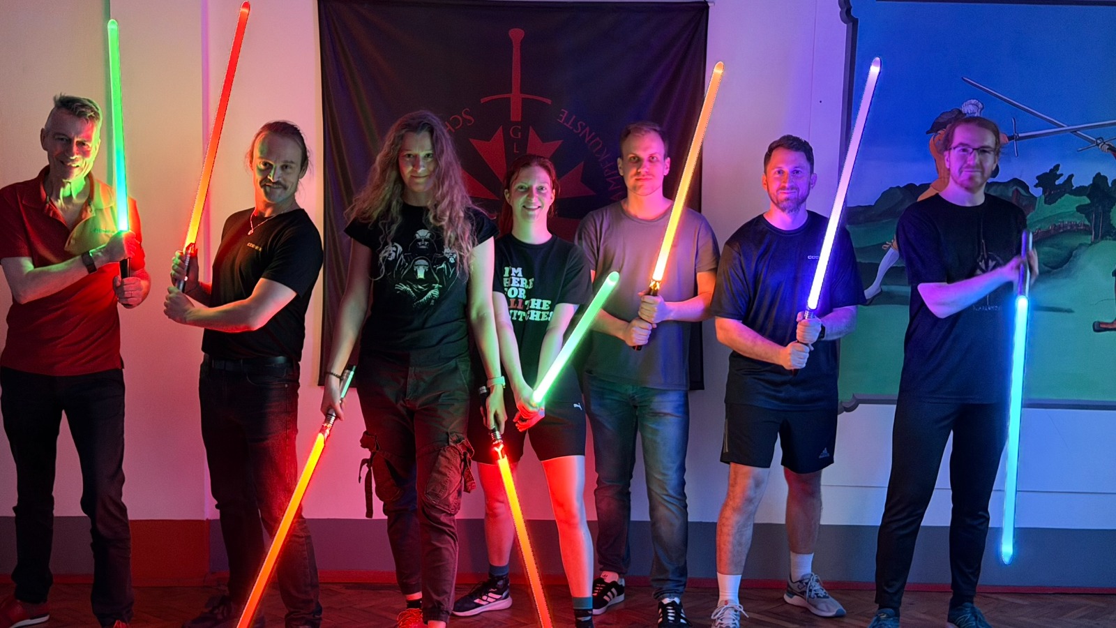 Group of eight participants with glowing blades in front of the Gladiatores banner